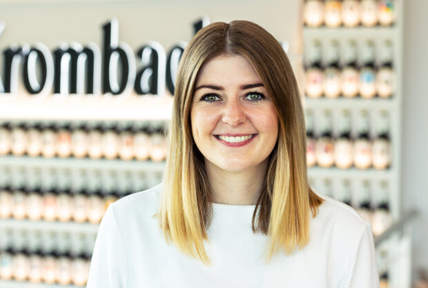 Portrait von Sara Schulte, Recruiterin, hat blonde schulterlange Haare, trägt eine weiße Bluse und lächelt freundlich in die Kamera.