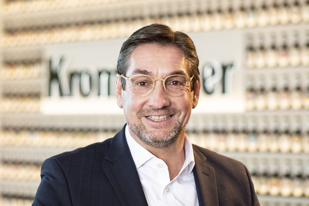 Portrait von Volker Arens, Head of People & Culture, lächelt in die Kamera. Er hat Braune Haare, eine beige Brille und trägt ein weißes Hemd mit schwarzem Anzug.
