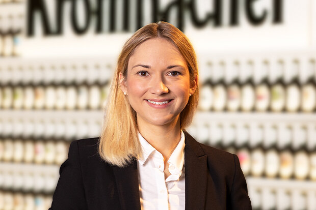 Portrait von Sina Bügeler, HR Business Partnerin, hat blonde Haare und trägt ein weißes Hemd mit schwarzem Blazer. Sie lächelt in die Kamera.