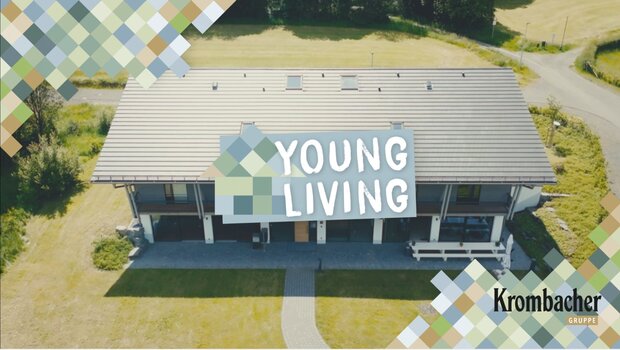 Das 'Young Living' Gebäude steht auf einer grünen Wiese, zwischen Bäumen und einer Straße.