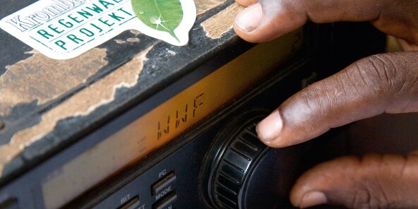 Close up von einer Hand, welche an einem Knopf an einem Radio dreht.