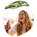 Junge Frau mit langen, gewellten Haaren reicht einem anderen ein Eis im Hörnchen bei sonnigem Sommerfest
