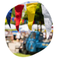 Bunte Wimpel in Rot, Gelb, Weiß und Blau beim Sommerfest mit unscharfem Hintergrund von Menschen und historischen Fahrzeugen